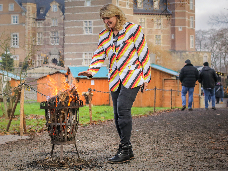 Sabine warmt haar handen bij een vuurtje op de kerstmarkt bij Schloss Merode in Duitsland