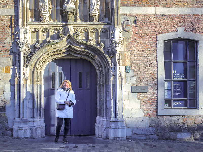 Sabine bij de mooi bewerkte deur van de Schatkamer van de Dom van Aken in 2022