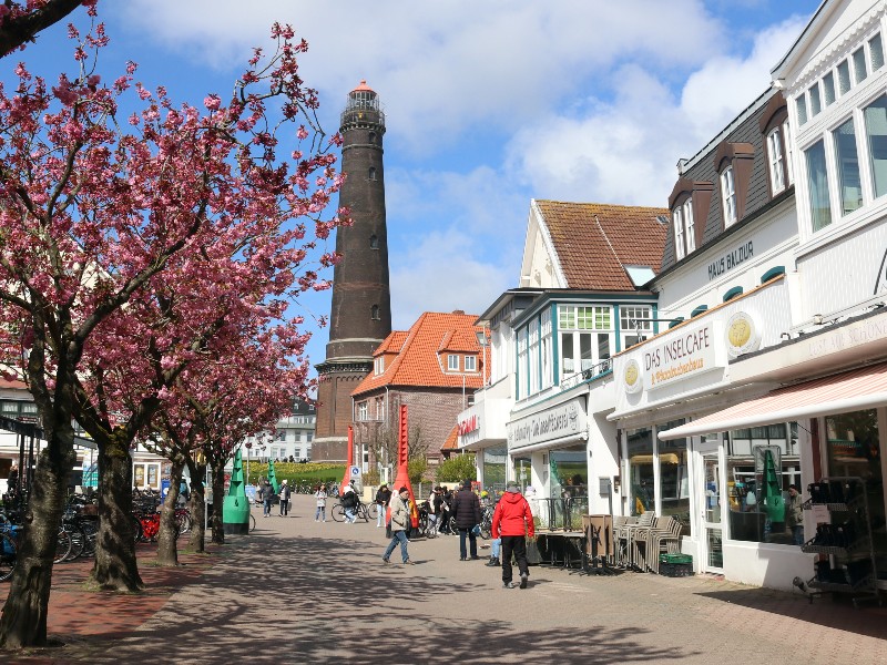 Winkelstraatje in Borkum, met de nieuwe vuurtoren op de achtergrond