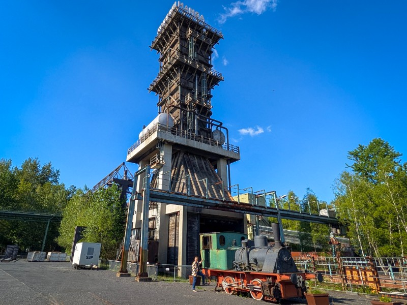 Patrick bij de oude locomotief en de toren van Kokerei Hansa